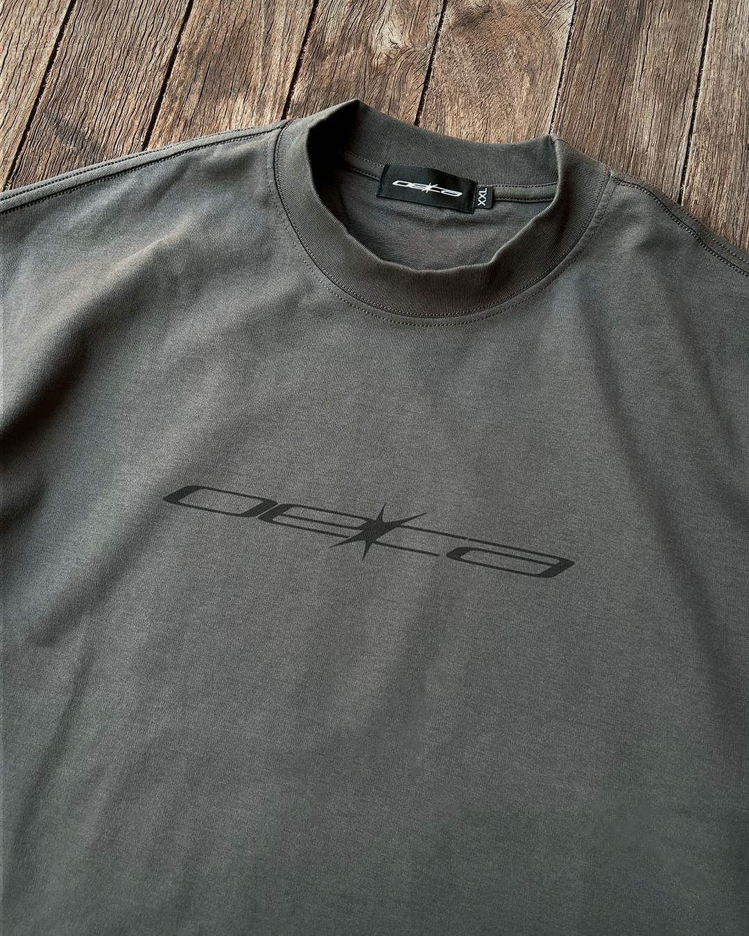Gray t-shirt with a logo on a wooden surface