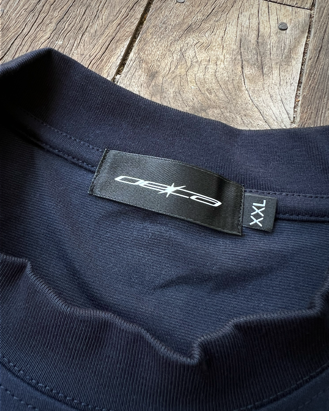 Navy blue shirt with a brand label on a wooden surface