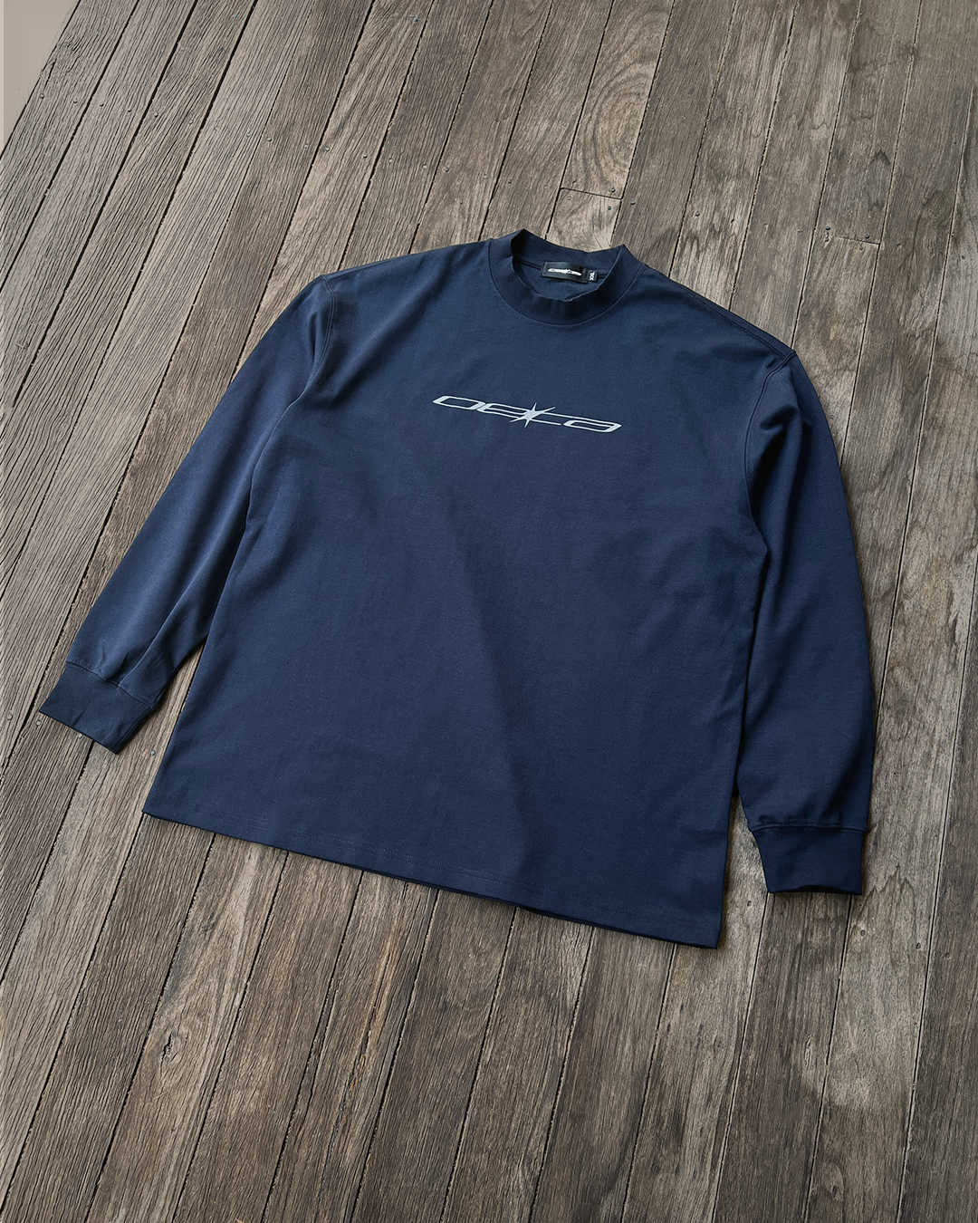 Navy long-sleeve shirt with a logo on a wooden floor