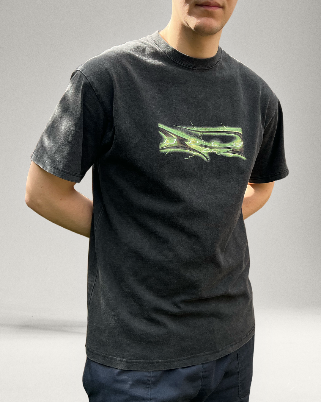 Person wearing a black t-shirt with a green logo on a gray background
