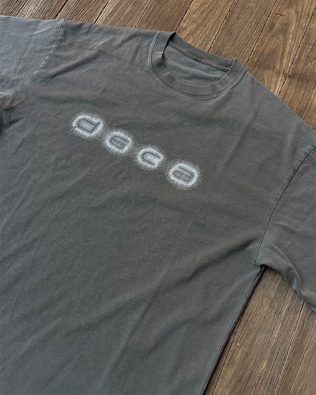 Gray t-shirt with 'DECO' logo on a wooden surface