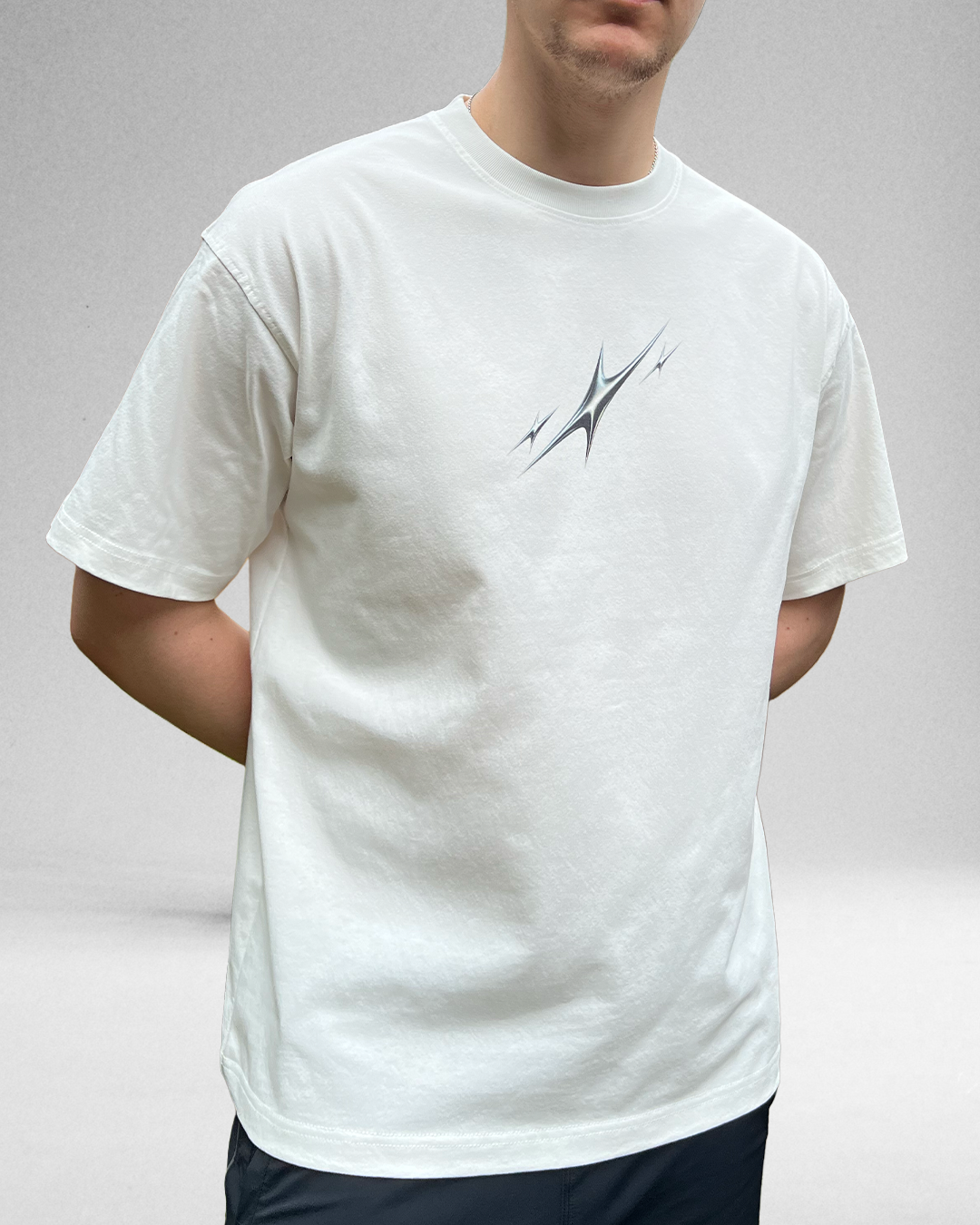 Person wearing a white t-shirt with a abstract stars design on a plain background