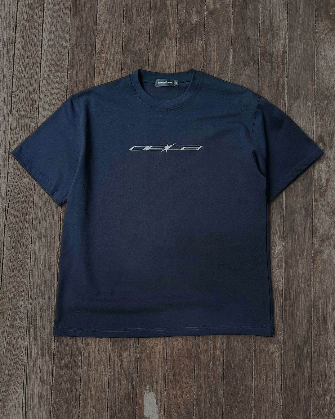 Navy blue t-shirt with a logo on a wooden surface