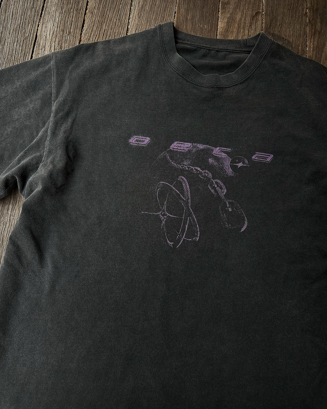 Black t-shirt with a purple graphic design on a wooden surface