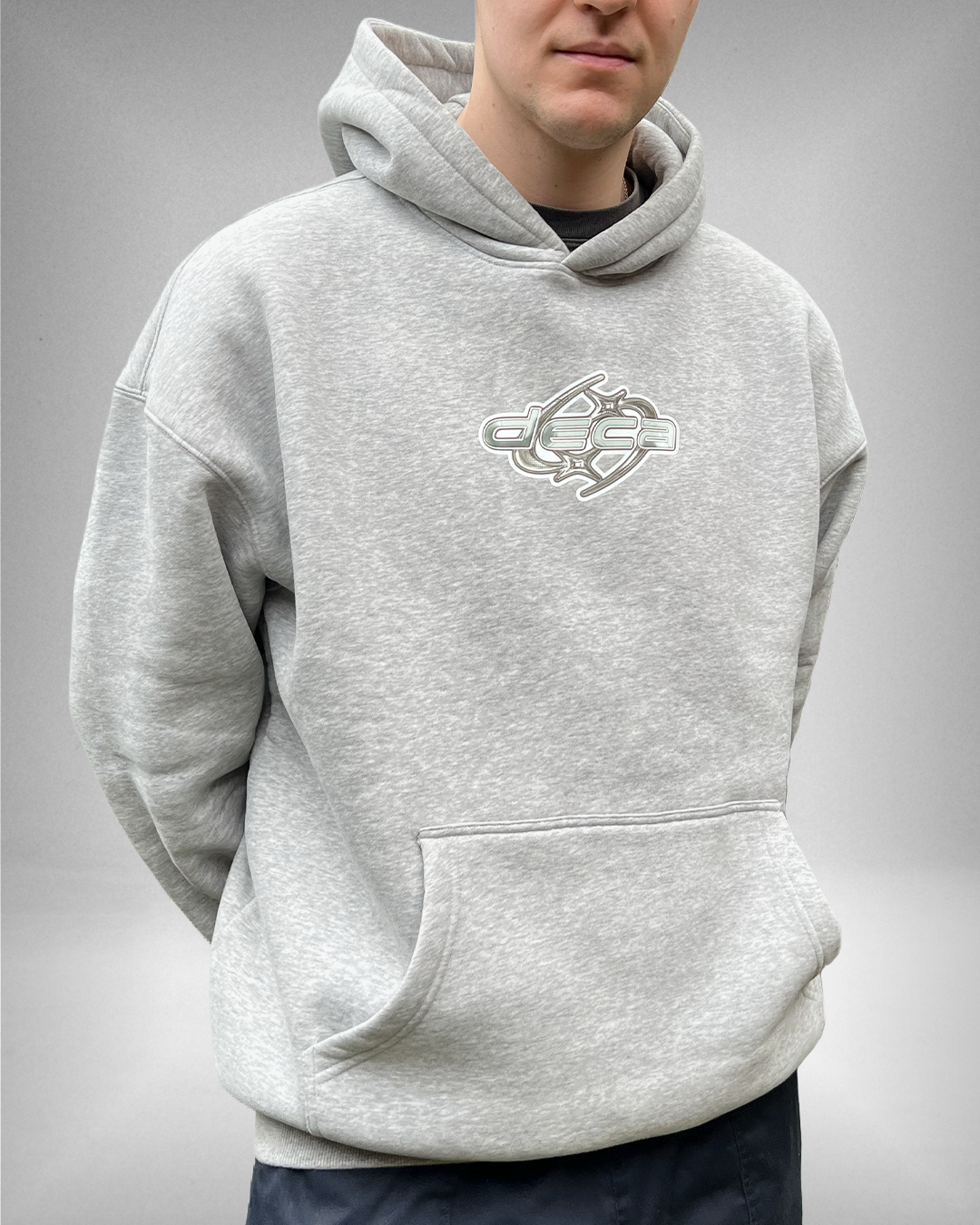 Person wearing a gray hoodie with a logo on a plain background