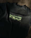 Black t shirt with green graphic design on a wooden surface
