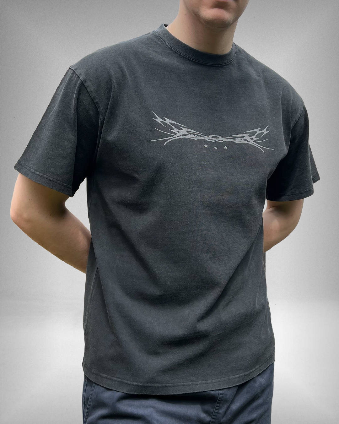 Person wearing a black t-shirt with a off green graphic design on a plain background